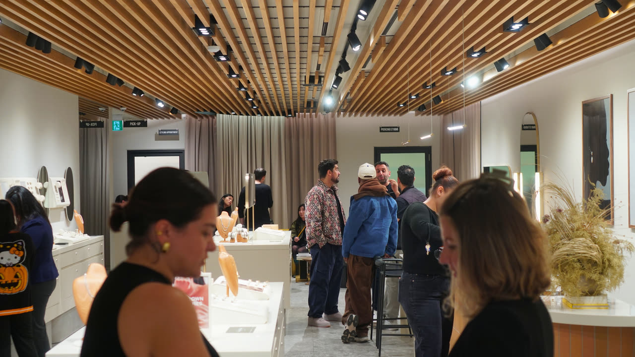 Guests standing and talking across the Mejuri Ossington store, under a slatted wood ceiling, with jewellery cases along the walls.